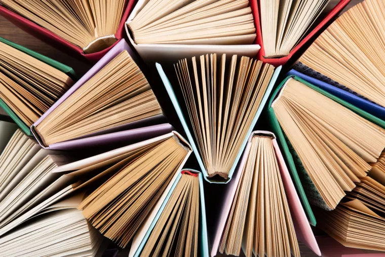 Mehrere leicht geöffnete Bücher in der Draufsicht fotografiert.