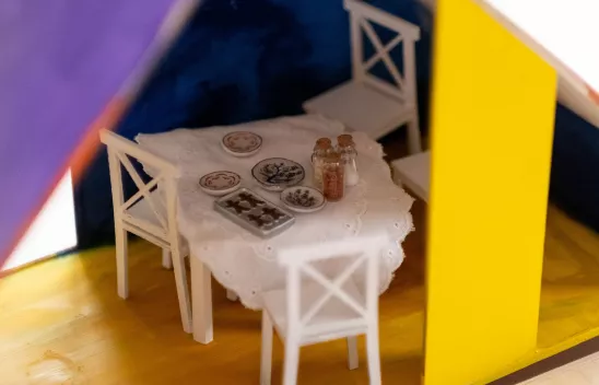 Ein Esstisch in einem Puppenhaus ist gedeckt.