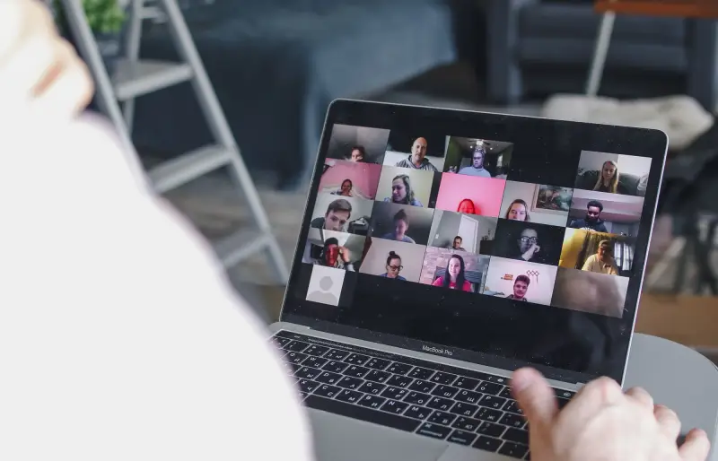 Blick auf einen Laptop, auf dessen Bildschirm mehrere Personen in einer Videokonferenz zu sehen sind