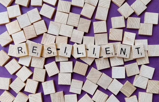 Holzplättchen, auf denen in einzelnen Buchstaben das Wort "RESILIENT" steht Holzplättchen, auf denen in einzelnen Buchstaben das Wort "RESILIENT" steht