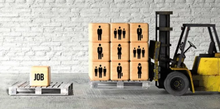 Ein Hubwagen trägt eine Palette mit Holzklötzen, auf denen Menschen aufgemalt sind. Links daneben liegt eine Palette auf der ein Klotz mit der Aufschrift "Job" liegt.