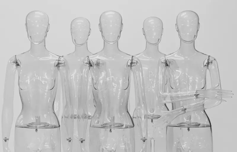 Transparente Schaufensterpuppen stehen vor einer weißen Wand.