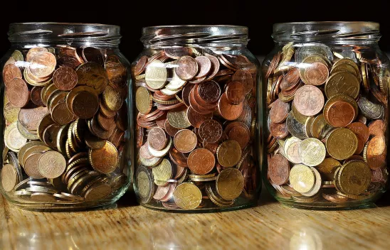 Drei Schraubgläser sind mit Cent-Stücken gefüllt.
