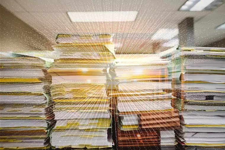 Aktenstapel hinter einem digitalen Lichstrahl.