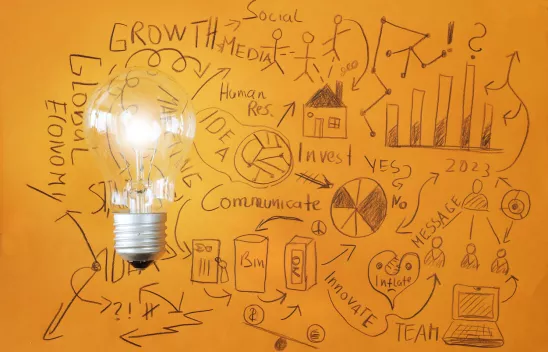 Kritzeleien auf orangenem Grund. Links liegt frotal eine große Glühbirne auf der Zeichnung.