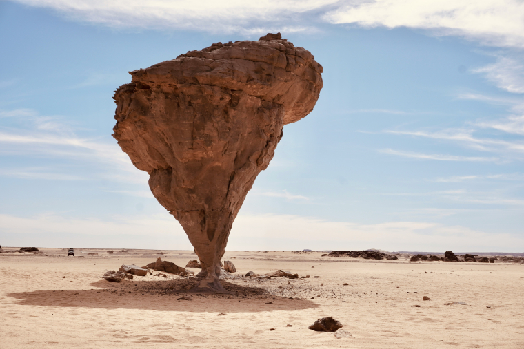 Das Bild zeigt einen erodierten Felsen in der Wüste, der nach unten spitz zuläuft und an eine extreme Form der "Bevölkerungspyramide" erinnert.