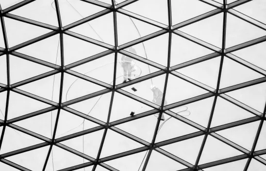 Zwei Arbeiter*innen beim Reinigen einer Glasfassade