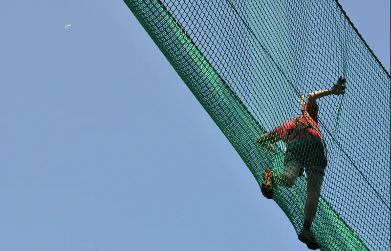 Eine Person überquert eine Netzbrücke, von unten fotografiert. Eine Person überquert eine Netzbrücke, von unten fotografiert.
