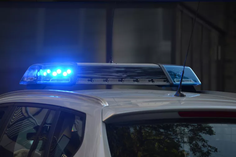 Der Ausschnitt eines Polizeiautos, auf dessen Dach Blaulicht leuchtet. 