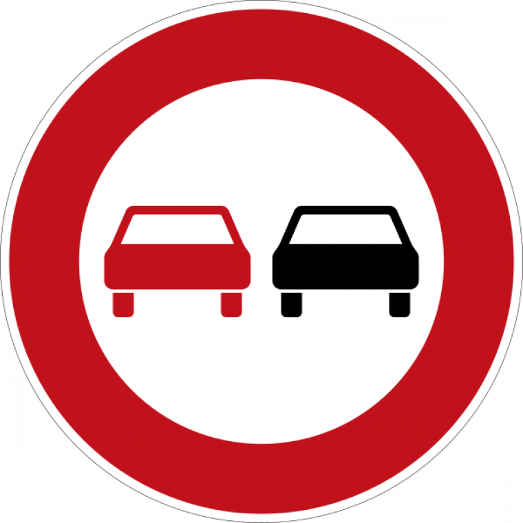 Ein Überholverbotsschild: Ein roter Kreis in dem links ein rotes Auto und rechts ein schwarzes Auto abgebildet sind. 