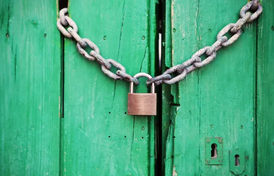 Metallenes  Vorhängeschloss an einer Kette zum Verschluss einer mintgrünen Holztür