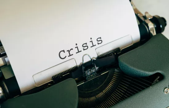 Eine Schreibmaschine, in der ein Blatt Papier liegt, auf dem das Wort "Crisis" steht Eine Schreibmaschine, in der ein Blatt Papier liegt, auf dem das Wort "Crisis" steht